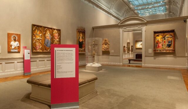 An example of the freestanding, bright pink signs that demarcated the installation in the 13th–15th Century Art gallery space, with a painting by Stephen Towns visible on the wall