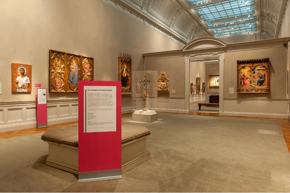 An example of the freestanding, bright pink signs that demarcated the installation in the 13th–15th Century Art gallery space, with a painting by Stephen Towns visible on the wall